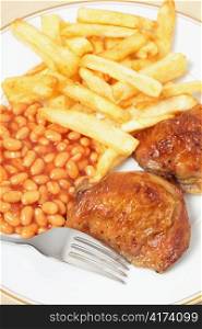 A meal of lemon chicken with french fries and baked beans