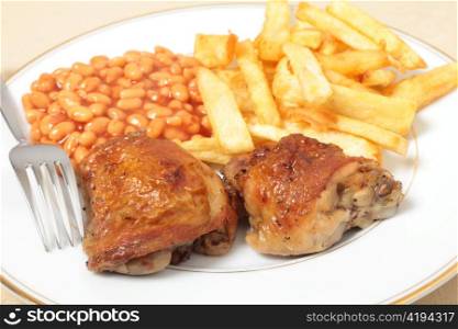 A meal of lemon chicken with french fries and baked beans