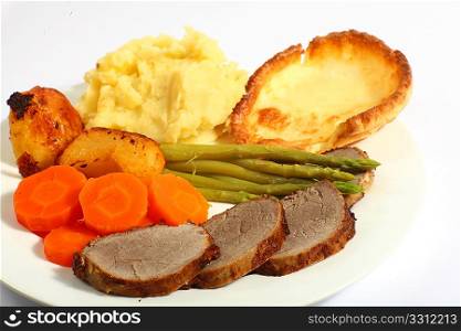 A meal of roast beef with carrots, mashed potatoes, asparagus and Yorkshire pudding.