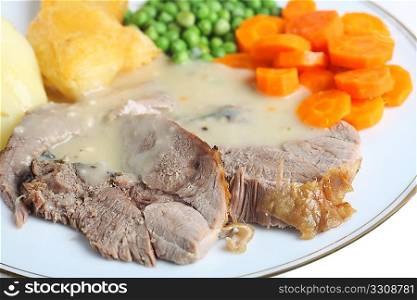 A meal of roast lamb with roasted potatoes, boiled peas and boiled sliced carrots