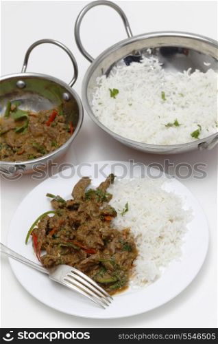 A meal of spiced lamb curry with coriander leaves and slivers of red and green chillies, served with plain boiled rice, high angle view