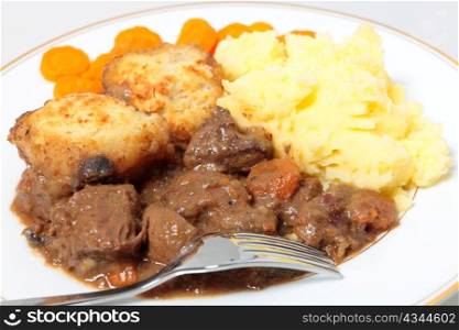 A meal of steak and kidney stew with suet dumplings, boiled carrots and mashed potatoes