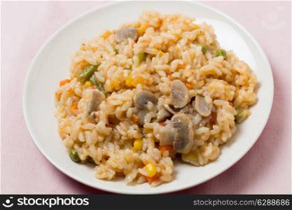 A meal of vegetable risotto with mushrooms, sweetcorn, carrot, green beans