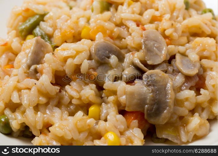 A meal of vegetable risotto with mushrooms, sweetcorn, carrot, green beans