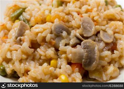 A meal of vegetable risotto with mushrooms, sweetcorn, carrot, green beans