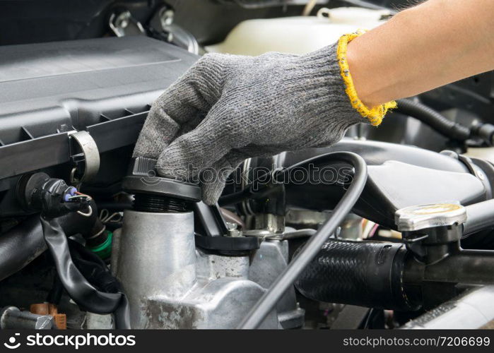 A mechanic is opening the oil cap from a car engine.