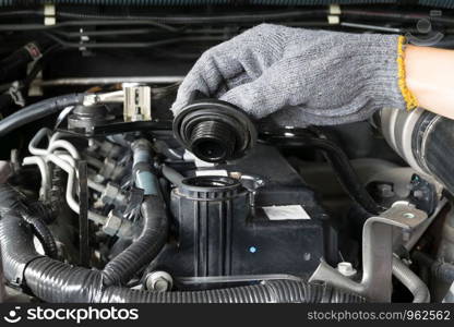 A mechanic is opening the oil cap from a car engine.