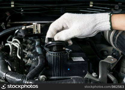 A mechanic is opening the oil cap from a car engine.