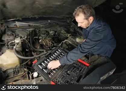 A mechanic repairing an engine of an old car.