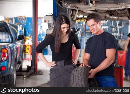 A mechanic showing the tread of a tire to a female customer