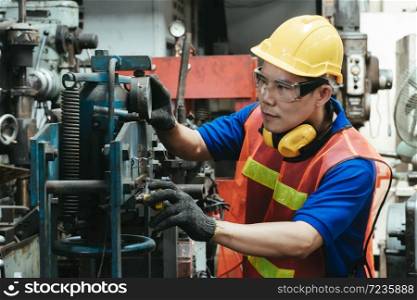 A mechanical engineer or worker with yellow safety helmet and goggles at work on production in a factory.