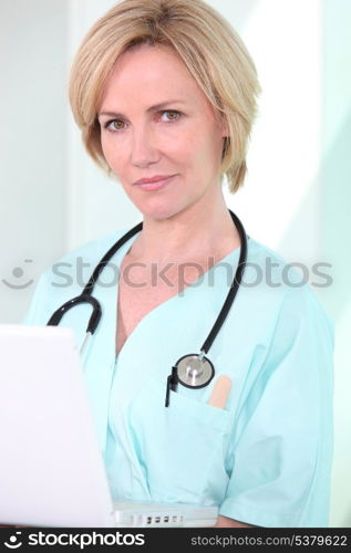 A medical professional looking at her laptop