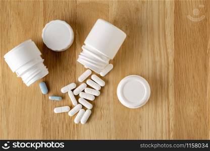 A medical set-up. Plastic white and glass bottles. Medicinal blue and white pills on a wooden table. A medical set-up. Plastic white and glass bottles. Medicinal blue and white pills.