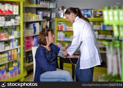 A Medical worker examining senior woman in a pharmacy. Medical worker examining senior woman in a pharmacy