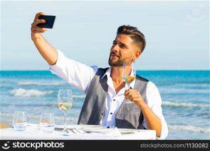 A men make a selfie on the beach with a glass of champagne. Lifestyle concept and celebration.. A men make a selfie on the beach