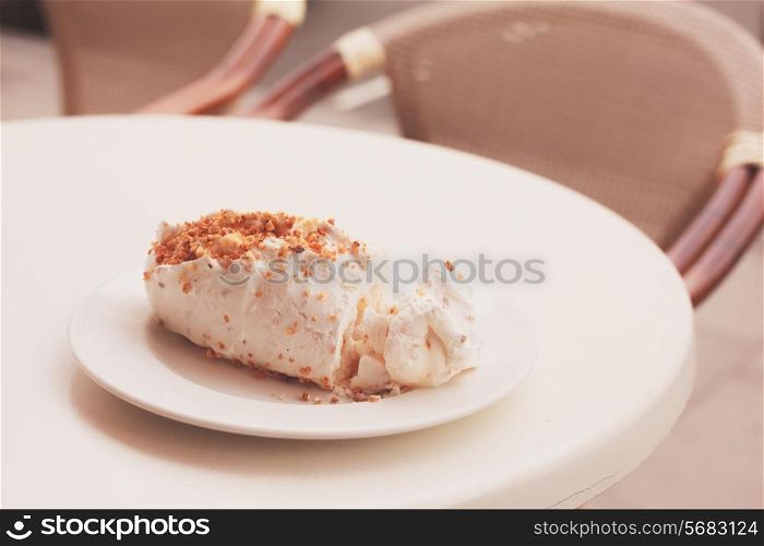 A meringue on a plate outdoors on a table at a cafe