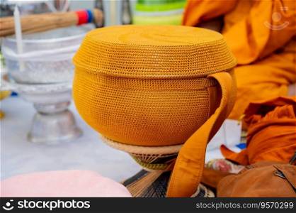 A metal alms bowl covered with golden-orange cloth to receive food from laypeople and people who believe in Buddhism.