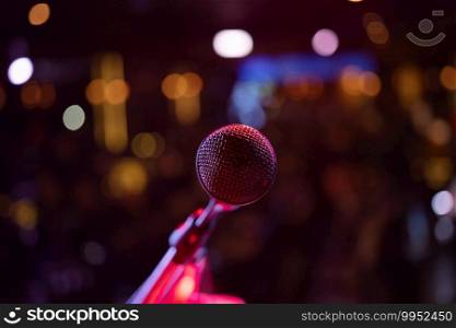 A microphone on stage concert with colorful lighting laser beam spotlight show in disco pub club bar background for party music dancing festival performance. Entertainment nightlife. Celebration event