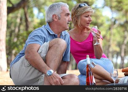 a mid age couple having a picnic in a pine forest