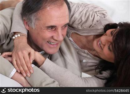 A middle age couple fooling around in bed.