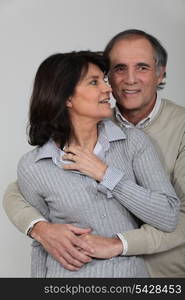 A middle age couple hugging.