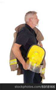 A middle age firefighter man standing in profile with his jacket overhis shoulder and helmet in his hand, isolated for white background