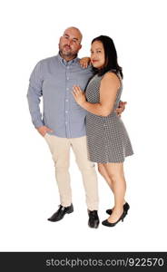 A middle age Hispanic couple standing in the studio arm in arm and smiling into the camera, isolated for white background