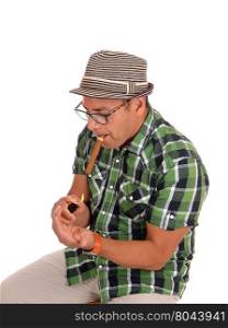 A middle age Hispanic man lightening his big cigar, sitting and wearing abeige hat, isolated for white background.