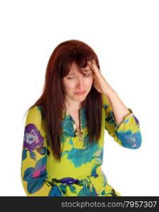 A middle age woman in a colorful dress with her hand on her head, cryingfor the bad headache, isolated for white background.