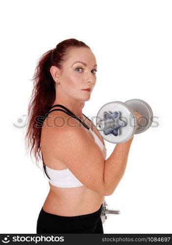 A middle age woman standing in profile lifting her dumbbells whit her long red hair and workout outfit, isolated for white background