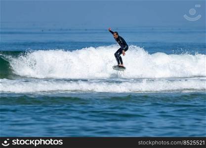 A middle aged man doing some foil surfing or hydrofoil surfing in the sea on a bright sunny day.
