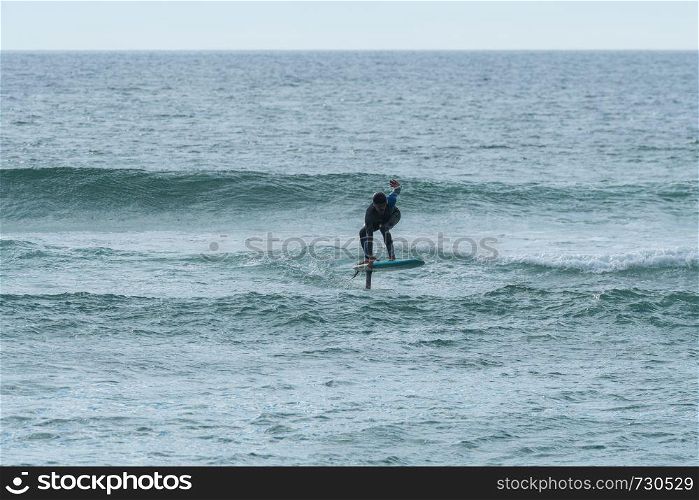 A middle aged man doing some foil surfing or hydrofoil surfing in the sea.