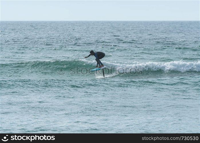 A middle aged man doing some foil surfing or hydrofoil surfing in the sea.