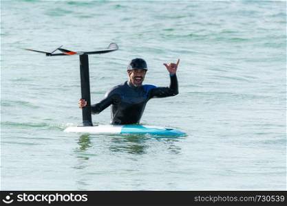 A middle aged man is finishing some foil surfing or hydrofoil surf training in the sea.
