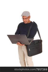 A middle ages Hispanic man standing isolated for white backgroundworking on his laptop with his bag over his shoulder.