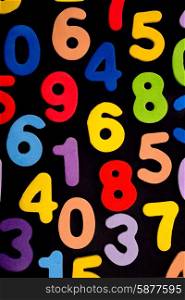 A mix of single digit numbers of different biright colours on a black background.