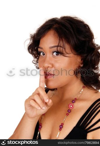 A mixed raced woman, looking into the camera holding her finger overher mouth gesturing silence, isolated for white background.