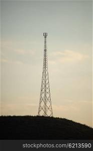 A mobile phone tower stand on a hill in the distance.