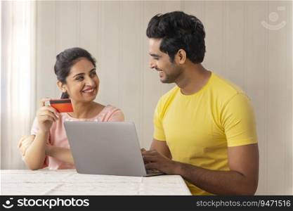 A MODERN COUPLE SITTING AT HOME AND DOING ONLINE TRANSACTION