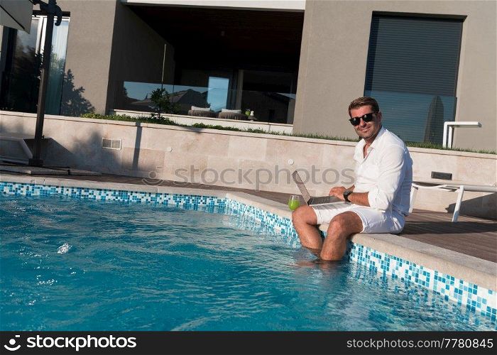 A modern elderly man enjoys the pool while working on his laptop next to a modern luxury house. Selective focus. High-quality photo. A modern elderly man enjoys the pool while working on his laptop next to a modern luxury house. Selective focus 