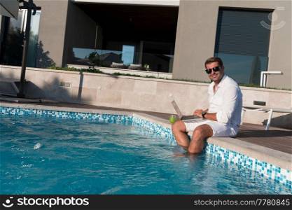 A modern elderly man enjoys the pool while working on his laptop next to a modern luxury house. Selective focus. High-quality photo. A modern elderly man enjoys the pool while working on his laptop next to a modern luxury house. Selective focus 