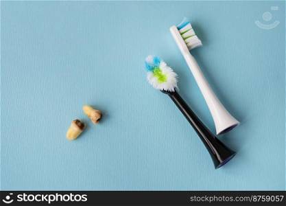 A modern electric toothbrush on a blue background next to extracted wisdom teeth affected by caries. Tooth extraction operation. Hygiene concept for daily care. Old and new toothbrush. A modern electric toothbrush on a blue background next to extracted wisdom teeth affected by caries. Tooth extraction operation. Hygiene concept for daily care. Old and new toothbrush.