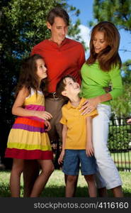 A modern family of father, mother, daughter and son playing together and having fun in a park