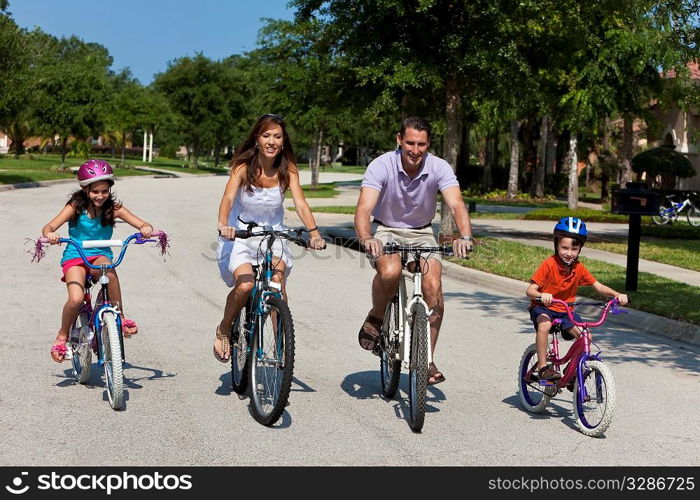 A modern family of two parents and two children, a boy and a girl, cycling together.