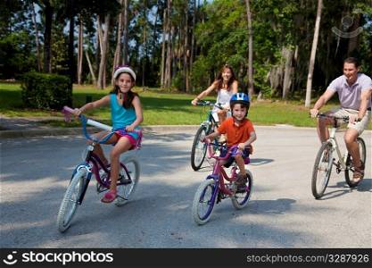 A modern family of two parents and two children, a boy and a girl, cycling together.