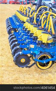 A modern multi row planter and distribution pipes with working mechanisms for pneumatic precise seed distribution against the background of a yellow stubble field. Vertical image. Copy space.. Multi row seeder with a mechanism for precise seed distribution used in agriculture.