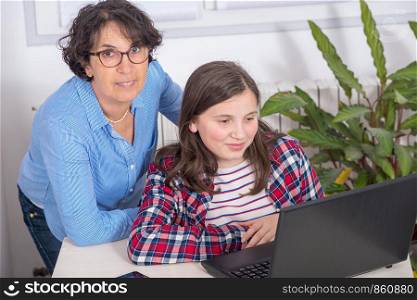 a mom and daughter using a laptop at home