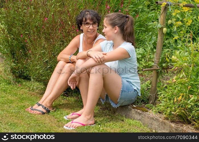 a mom and her teen daughter sitting in the grass