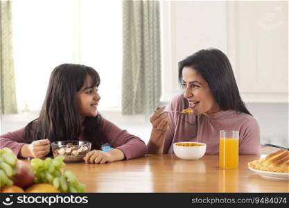 A MOTHER AND DAUGHTER HAPPILY EATING BREAKFAST TOGETHER