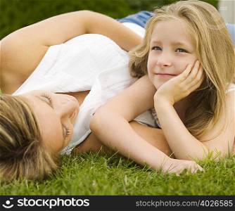 A mother and daughter lying on a lawn